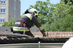 Tetőn térdelve háttal dolgozik egy tűzoltó