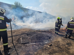 Középen füstölgő szalmabálák két oldalt tűzoltók