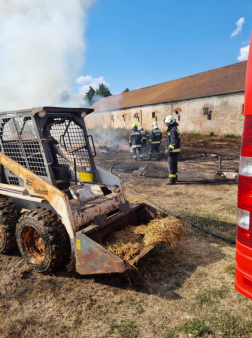 Bobcat eleje háttérben tűzoltók füstölgő szalmakupac