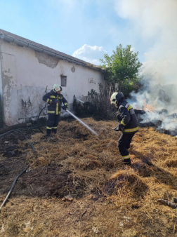 Egy tűzoltó vízsugárral a másik kéziszerszámmal végzi az oltást