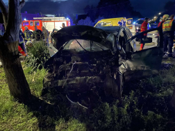 Autó összetört eleje egy fa mellett mögötte tűzoltóautó és mentőautó