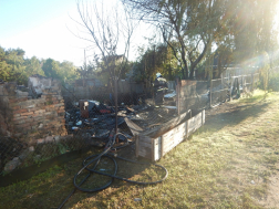A telek kerítése mögött a leégett ház maradványai