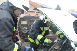 Két tűzoltó áramtalanítja az autót a motortérnél