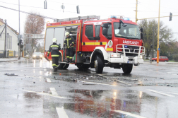 Középen tűzoltóautó előtte az esős burkolaton törmelékek