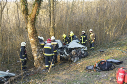 Tűzoltók feszítővágóval dolgoznak az összeroncsolódott autónál