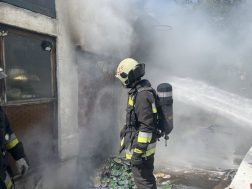 Tűzoltó háttal a füstölő garázs előtt