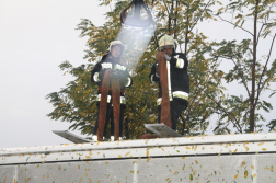 Hevederrel két tűzoltó a busz tetején