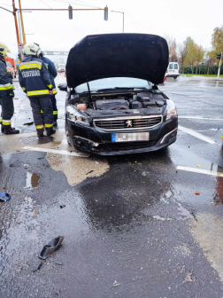 Autó felnyitott motorháztetővel mellette tűzoltók