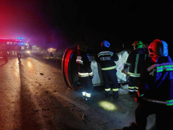 felborult autó előtt tűzoltók a sötétben