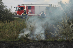 Füstölgő árokpart fölött tűzoltóautó tűzoltókkal