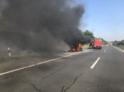 Távolban ahogy a tűzoltók megérkeznek az égő autóhoz