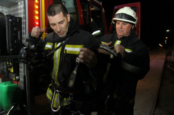 Tűzoltó hátáról segít egy másik levenni a hordkeretet