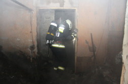 Kégett melléképület ajtajában háttal egy tűzoltó