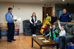 Kirendeltségvezető tűzoltó sisakot tart a kezében rajta égő gyertya szemben vele a gyerekek