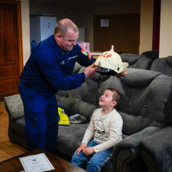 Az ünnepelt feje fölé tartja a tűzoltó sisakot egy tűzoltó